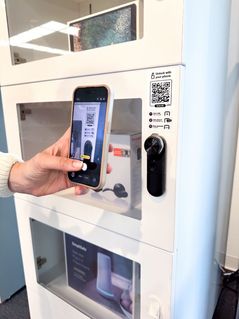 InVue LIVE 잠금 장치가 장착된 보안 캐비닛 문에 있는 ‘고객 셀프 액세스(Customer Self-Access)’ QR 코드를 스캔하는 쇼핑객
