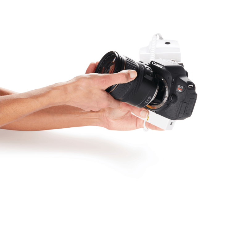 손에 든 카메라, 흰색 보안 디스플레이 위에 놓여 있음